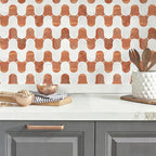 Kitchen counter with geometric patterned backsplash, gray cabinets, and kitchen utensils.