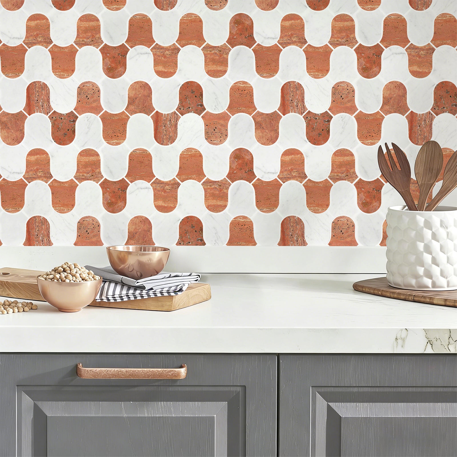 Kitchen counter with geometric patterned backsplash, gray cabinets, and kitchen utensils.