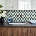 Bathroom with green and white geometric tile pattern, and wooden cabinet.