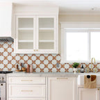 Modern kitchen with white cabinets, patterned backsplash, and marble countertop.