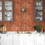 Modern kitchen with red patterned backsplash, white cabinets, and decorative elements.