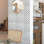 mosaic tile wall with geometric design, chair, and wooden cabinet in a room setting.