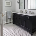 Bathroom with black vanity, white countertop, white tiled floor and decorative elements.
