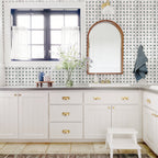 Bathroom with white vanity, mirror, and window with black trim.
