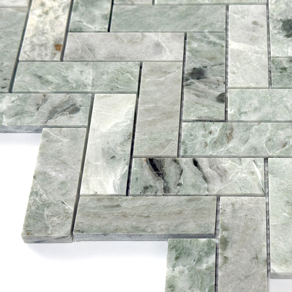Green marble tiles arranged in herringbone pattern on a white background