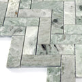 Green marble tiles arranged in herringbone pattern on a white background