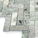 Green marble tiles arranged in herringbone pattern on a white background