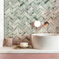 Bathroom with a green herringbone tile pattern on the wall, a white sink, and decorative items.