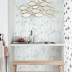 Decorative wall art with gold fish shapes on a light gray wall.