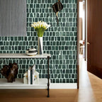 Green mosaic tile wall with decorative items on a shelf