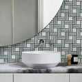 Bathroom vanity with a round white sink, marble countertop, and geometric patterned wall tiles.