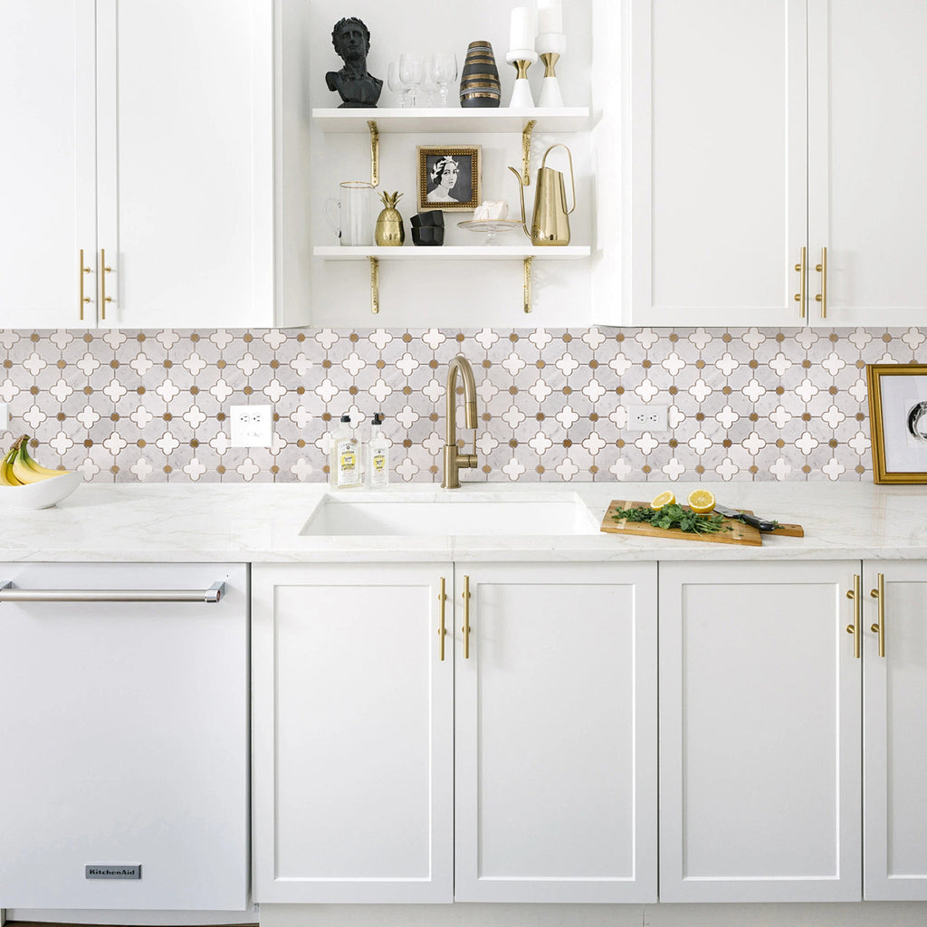 Modern kitchen with white cabinets, marble backsplash, and gold fixtures.