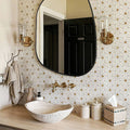 Bathroom with geometric tile pattern, round mirror, and decorative elements.