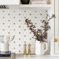 Decorative tile pattern on a wall with a vase of flowers and kitchen utensils.