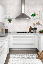 Modern kitchen with white cabinets, tiled backsplash, and stainless steel appliances.