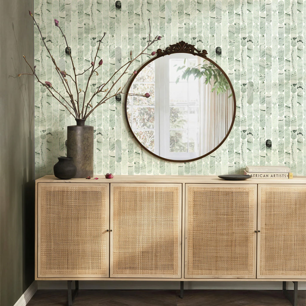 Wooden cabinet with rattan doors against a textured green wall with a round mirror.